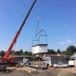crane lowers prefabricated classroom onto ground at Bishop