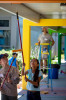 Students use extended pain rollers to paint a multi-colored hallway.