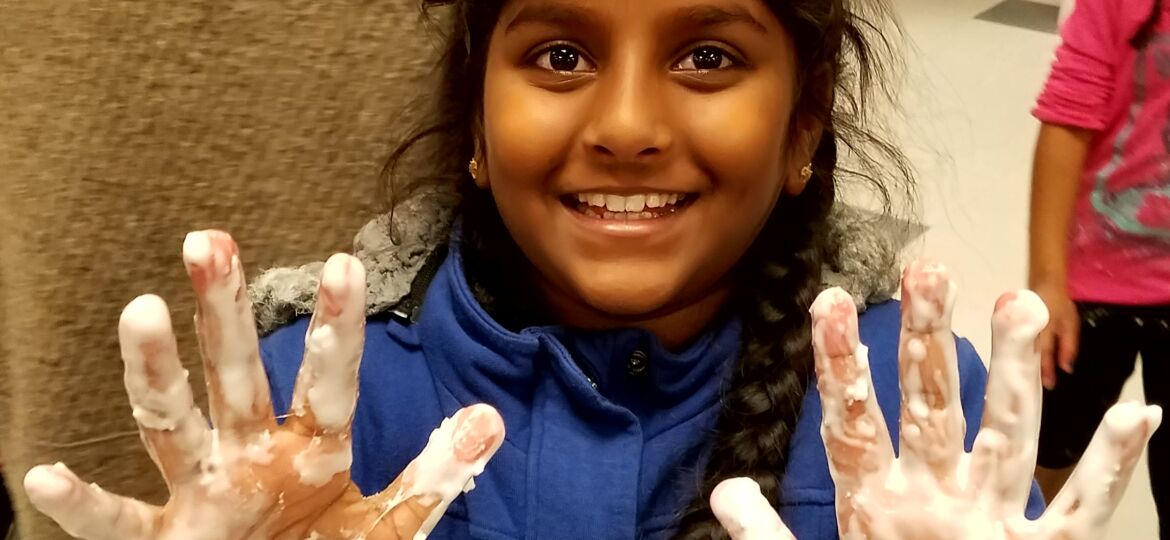 smiling student with sticky hands from science experiment